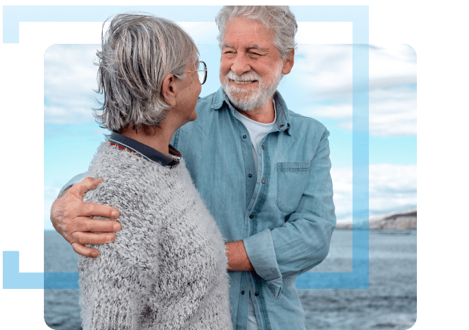 An older couple smiling as they walk along the beach. They are happy after choosing a leading asbestos law firm to help with their mesothelioma case.