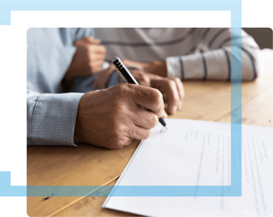 Hand holding a pen and signing a legal document at a mesothelioma law firm's office.